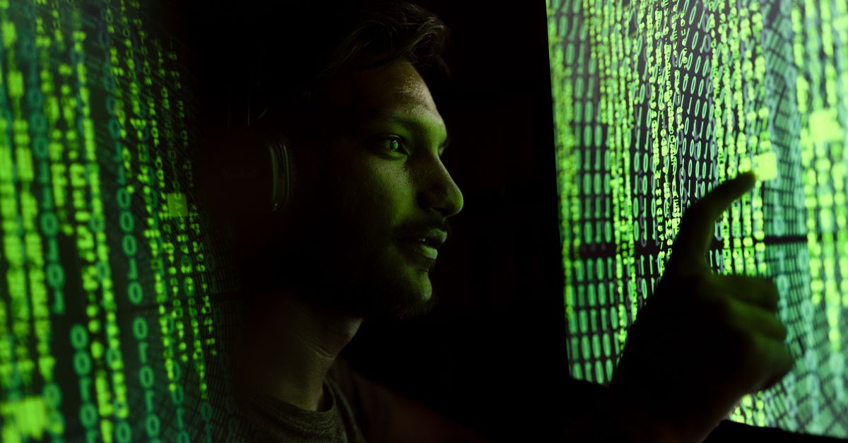 A person interacts with digital code on a screen, symbolizing cybersecurity technology.